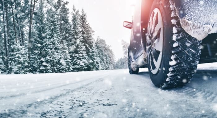 Car driving on a snowy road with snow-covered trees