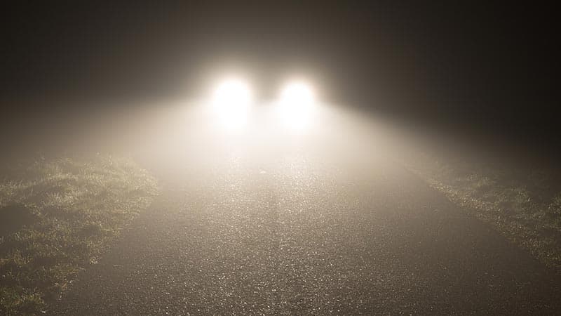 Car driving in foggy conditions with fog lights on